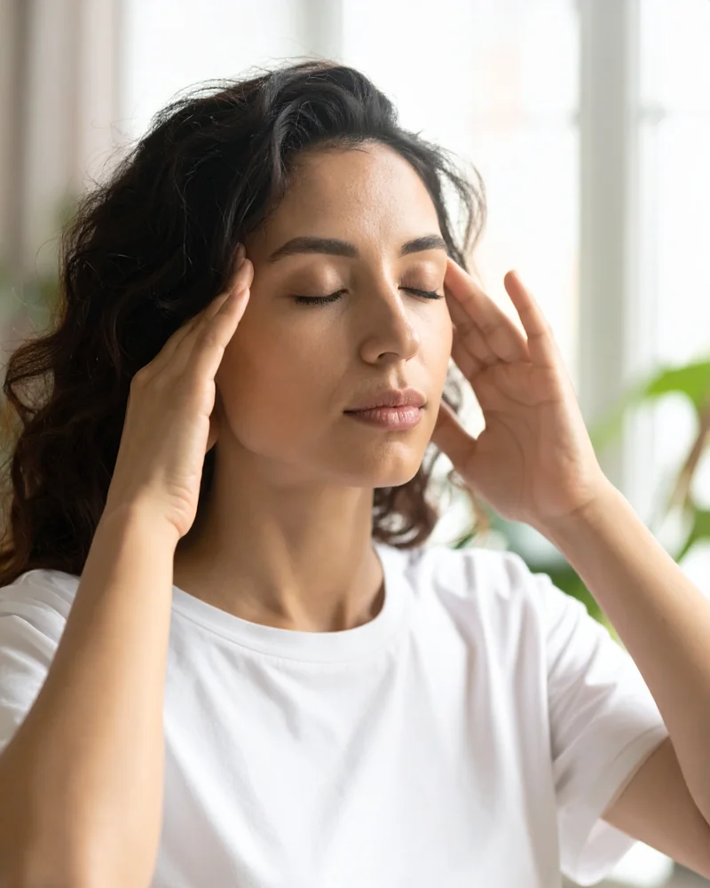 Femme les yeux fermés gérant le stress, mains sur les tempes